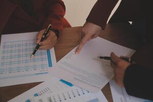 Group of confident business people point to graphs and charts to analyze market data, balance sheet, account, net profit to plan new sales strategies to increase production capacity. photo