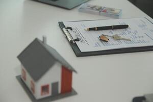 Real estate agent home sales broker is using a pen pointing to the house model and explains the business contract, rent, buy, mortgage, loan, or home insurance photo