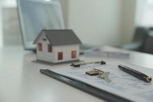 Real estate agent home sales broker is using a pen pointing to the house model and explains the business contract, rent, buy, mortgage, loan, or home insurance photo