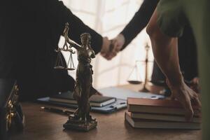 Lawyer shaking hands with a client making about documents, contracts, agreements, cooperation agreements with a female client at the lawyer's desk and a hammer at the table. photo