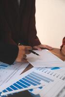 Group of confident business people point to graphs and charts to analyze market data, balance sheet, account, net profit to plan new sales strategies to increase production capacity. photo
