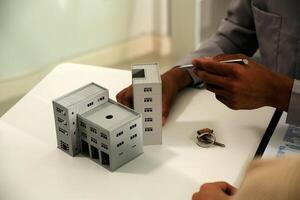 Real estate agent home sales broker is using a pen pointing to the house model and explains the business contract, rent, buy, mortgage, loan, or home insurance photo
