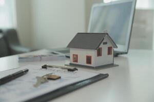Real estate agent home sales broker is using a pen pointing to the house model and explains the business contract, rent, buy, mortgage, loan, or home insurance photo