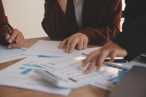 Group of confident business people point to graphs and charts to analyze market data, balance sheet, account, net profit to plan new sales strategies to increase production capacity. photo
