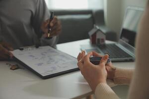 Real estate agent home sales broker is using a pen pointing to the house model and explains the business contract, rent, buy, mortgage, loan, or home insurance photo