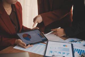 Group of confident business people point to graphs and charts to analyze market data, balance sheet, account, net profit to plan new sales strategies to increase production capacity. photo