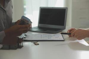 Real estate agent home sales broker is using a pen pointing to the house model and explains the business contract, rent, buy, mortgage, loan, or home insurance photo