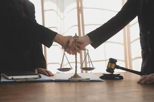 Lawyer shaking hands with a client making about documents, contracts, agreements, cooperation agreements with a female client at the lawyer's desk and a hammer at the table. photo
