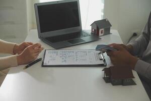 Real estate agent home sales broker is using a pen pointing to the house model and explains the business contract, rent, buy, mortgage, loan, or home insurance photo