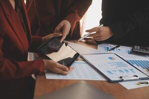 Group of confident business people point to graphs and charts to analyze market data, balance sheet, account, net profit to plan new sales strategies to increase production capacity. photo