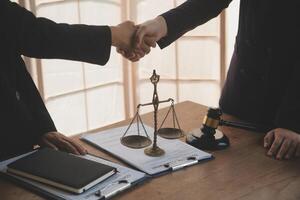 Lawyer shaking hands with a client making about documents, contracts, agreements, cooperation agreements with a female client at the lawyer's desk and a hammer at the table. photo