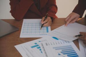 Group of confident business people point to graphs and charts to analyze market data, balance sheet, account, net profit to plan new sales strategies to increase production capacity. photo
