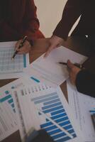 Group of confident business people point to graphs and charts to analyze market data, balance sheet, account, net profit to plan new sales strategies to increase production capacity. photo