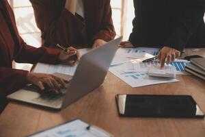 Group of confident business people point to graphs and charts to analyze market data, balance sheet, account, net profit to plan new sales strategies to increase production capacity. photo