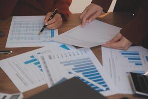 Group of confident business people point to graphs and charts to analyze market data, balance sheet, account, net profit to plan new sales strategies to increase production capacity. photo