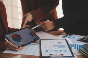 Group of confident business people point to graphs and charts to analyze market data, balance sheet, account, net profit to plan new sales strategies to increase production capacity. photo