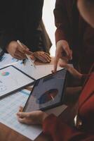 Group of confident business people point to graphs and charts to analyze market data, balance sheet, account, net profit to plan new sales strategies to increase production capacity. photo