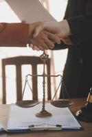 Lawyer shaking hands with a client making about documents, contracts, agreements, cooperation agreements with a female client at the lawyer's desk and a hammer at the table. photo