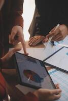 Group of confident business people point to graphs and charts to analyze market data, balance sheet, account, net profit to plan new sales strategies to increase production capacity. photo