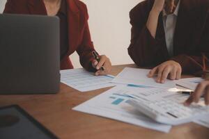 Group of confident business people point to graphs and charts to analyze market data, balance sheet, account, net profit to plan new sales strategies to increase production capacity. photo