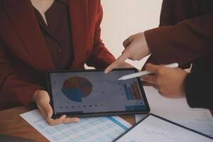 Group of confident business people point to graphs and charts to analyze market data, balance sheet, account, net profit to plan new sales strategies to increase production capacity. photo