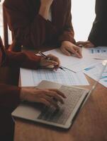 Group of confident business people point to graphs and charts to analyze market data, balance sheet, account, net profit to plan new sales strategies to increase production capacity. photo