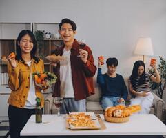 Happy friends making a toast with beer before eating pizza in a shared apartment. photo