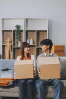 Young Asian couple relocating to a new house, joyfully packing and unpacking belongings. Expertise in moving, packing, togetherness, and creating a new home together. photo