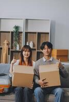 Young Asian couple relocating to a new house, joyfully packing and unpacking belongings. Expertise in moving, packing, togetherness, and creating a new home together. photo