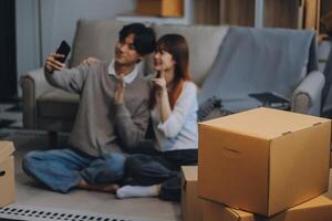 Young Asian couple relocating to a new house, joyfully packing and unpacking belongings. Expertise in moving, packing, togetherness, and creating a new home together. photo