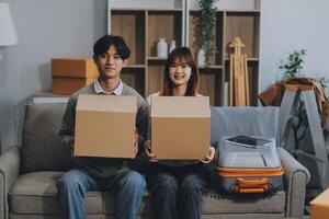 Young Asian couple relocating to a new house, joyfully packing and unpacking belongings. Expertise in moving, packing, togetherness, and creating a new home together. photo