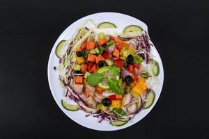 a plate of vegetables and meat on a black background photo