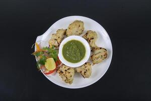 A plate with chicken on it and a bowl of sauce photo