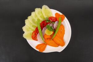 A plate with vegetables and fish on it photo