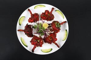 A plate with a Chicken lollipop on it photo
