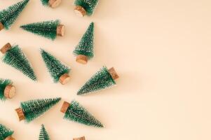 Trendy Christmas pattern made with green Christmas trees on pastel cream background. Minimal creative Christmas and New Year concept. Festive holiday backdrop. Xmas aesthetic. Flat lay. Copy space. photo