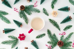 Christmas pattern made of green Xmas trees, snowy branches, candles, Christmas candies and pinecones with cup of coffee on white background. Creative Christmas and New Year concept. Winter flat lay. photo