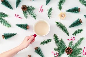 Christmas pattern made of green Xmas trees, snowy branches, candles, Christmas candies and pinecones with cup of coffee on white background. Creative Christmas and New Year concept. Winter flat lay. photo