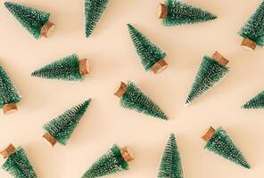 Trendy Christmas pattern made with green Christmas trees on pastel cream background. Minimal creative Christmas and New Year concept. Festive holiday pattern backdrop. Xmas aesthetic. Flat lay. photo