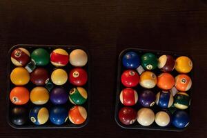 Billiard balls neatly arranged in two trays on a tabletop photo