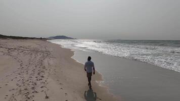 Man walking and running on sand dunes near the beach. Aerial image with drone following the man. Image from above. Health concept. video