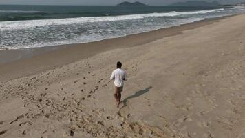 Man walking and running on sand dunes near the beach. Aerial image with drone following the man. Image from above. Health concept. video