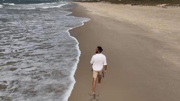 Man walking and running on sand dunes near the beach. Aerial image with drone following the man. Image from above. Health concept. video