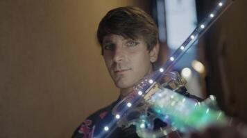 Man with intense gaze poses with colorful violin in hand video