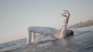 Dancer lying on the water poses on the beach video