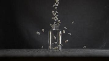 Falling Pills into Transparent Glass Bottle on Dark Background video