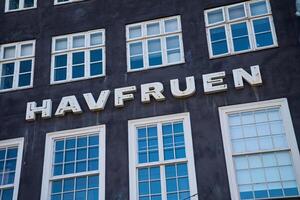 Facade of old historical building with inscription HAVFRUEN. Nyhavn Harbor in Copenhagen. Famous tourist spot in Denmark. Copenhagen, Denmark - June 26, 2024 photo