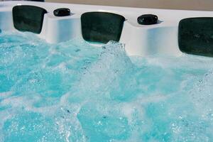 Close-up shot bubbling water in hot tub with headrests. Blue water in jacuzzi for relaxing and refreshing spa experience photo