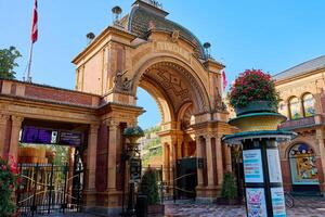 Main gate of entrance to Tivoli gardens amusement park with architectural arch in Copenhagen. Famous touristic attraction in Denmark. Copenhagen, Denmark - June 25, 2024 photo