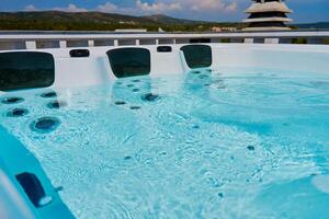 Close-up shot bubbling water in hot tub with headrests. Blue water in jacuzzi for relaxing and refreshing spa experience photo